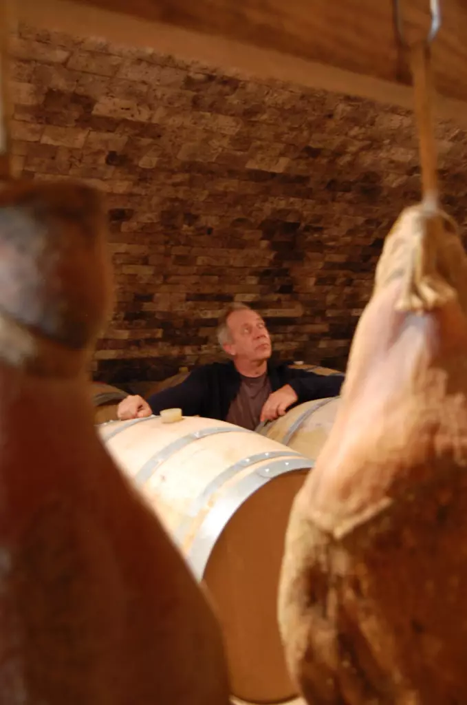 Stéphane Derenoncourt dans la cave du domaine de l'A. Accrochés au plafond les fameux jambons de Patrick Duler